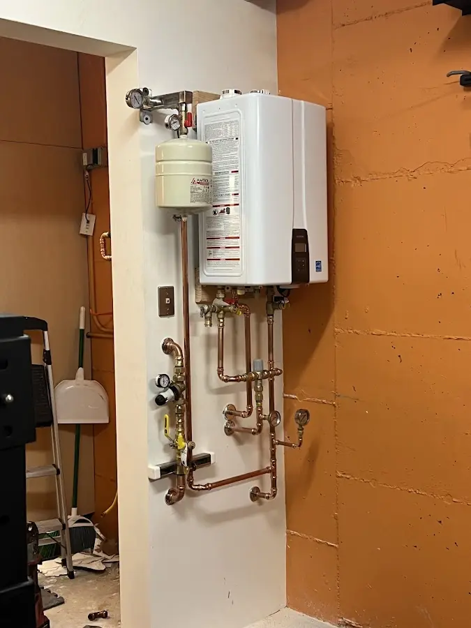 Plumbing technician inspecting water heater connections in Swartz Creek
